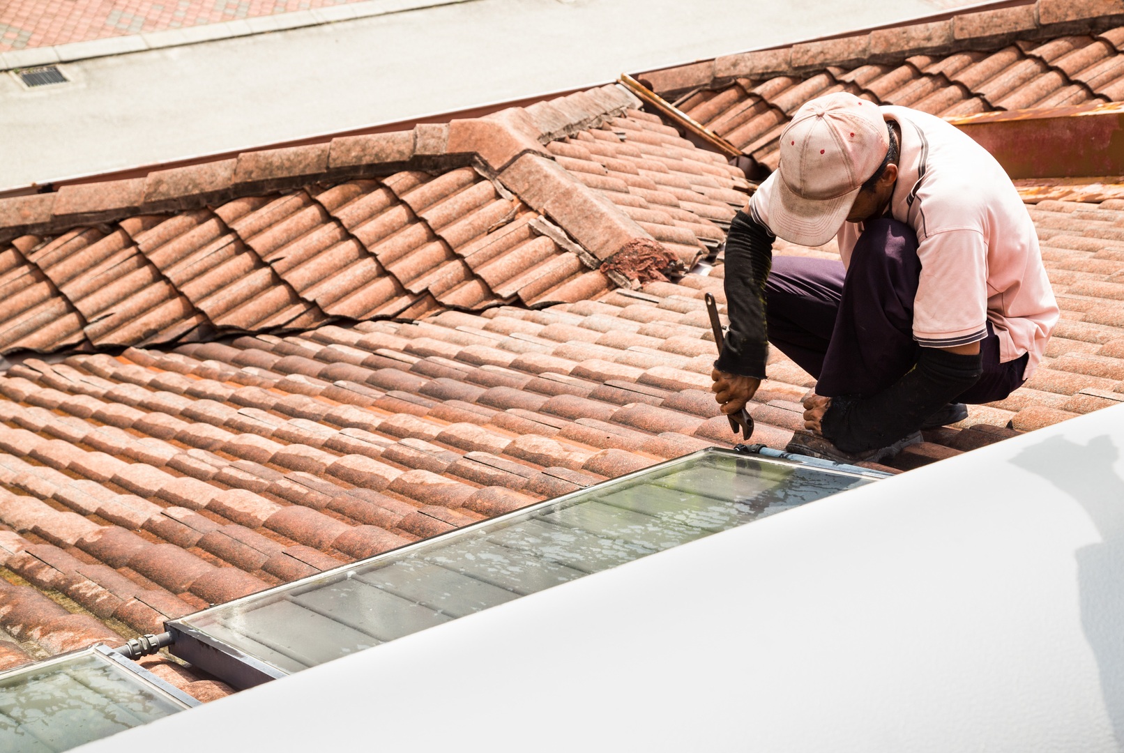 man on top of a roof and repairing the roof