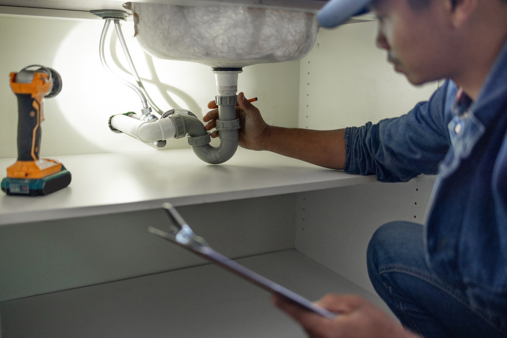 Plumber, sink maintenance check and plumbing data of a handyman in a kitchen. Water pipe installati.